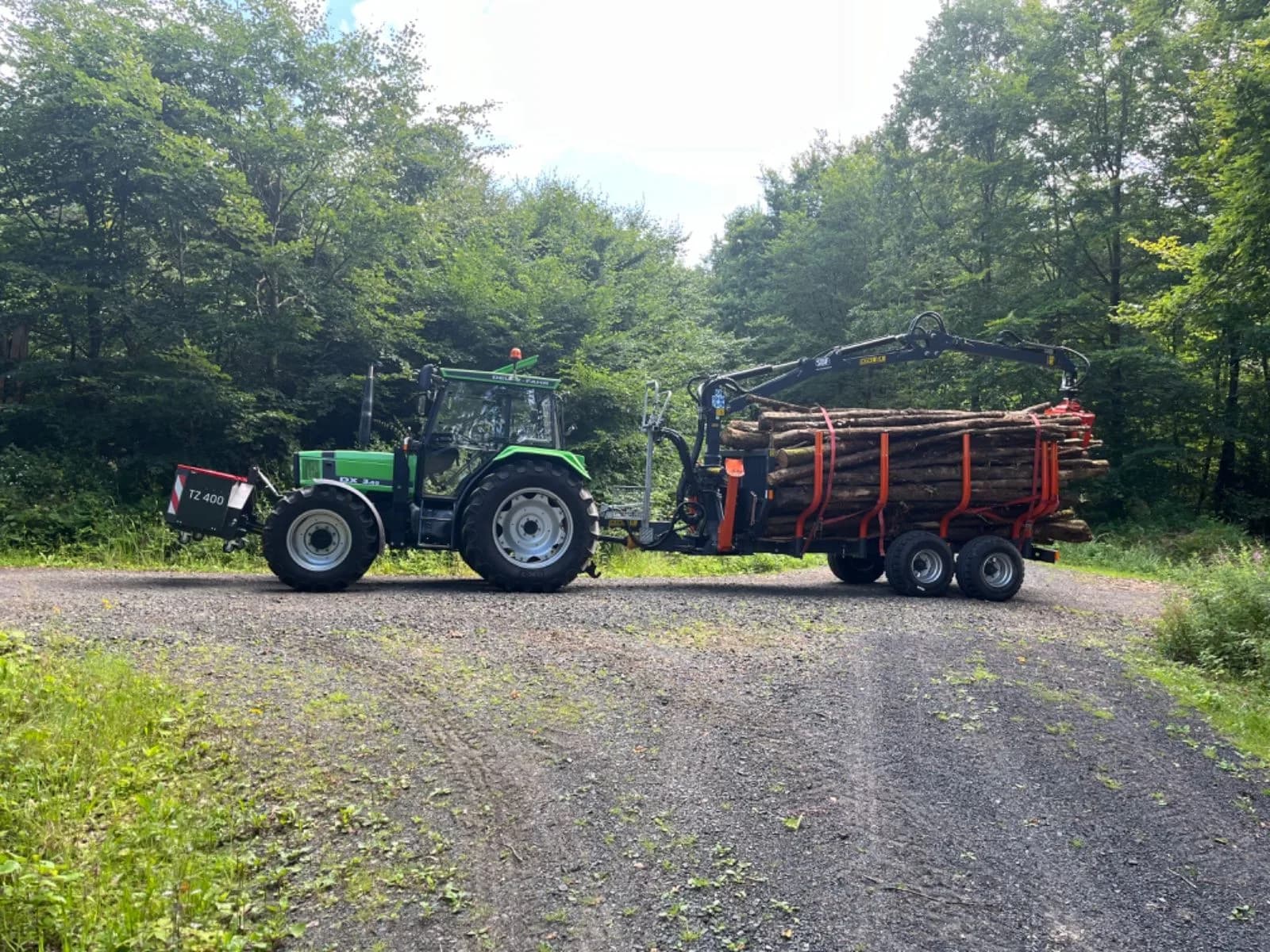 Traktor mit beladenem Rückewagen auf einem Waldweg