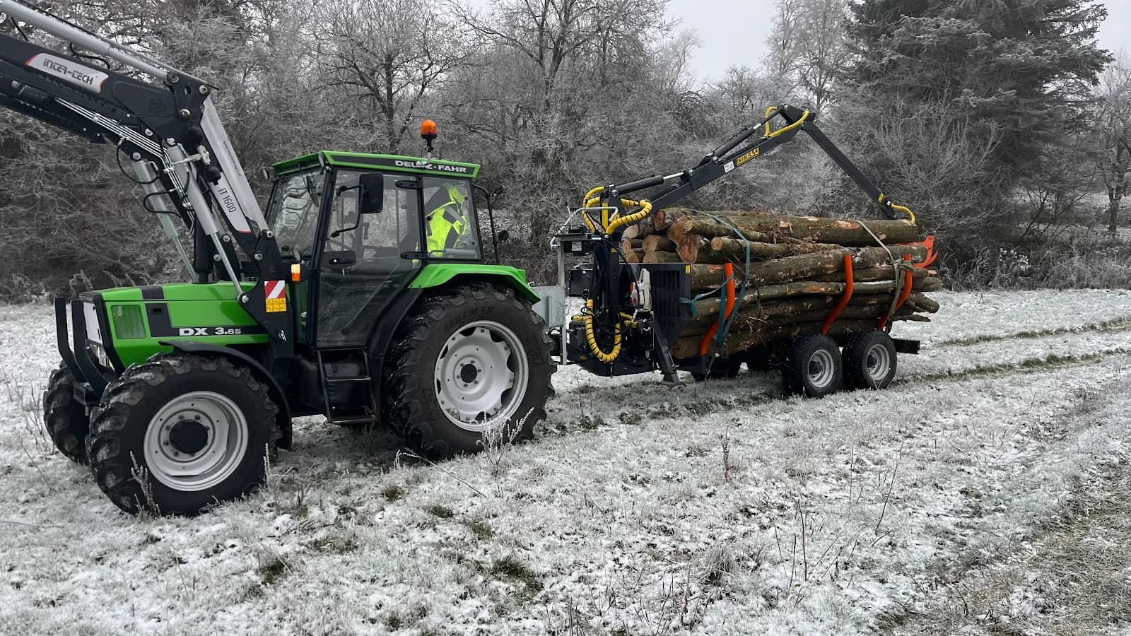 Traktor mit Rückewagen und Stammholz bei Raureif